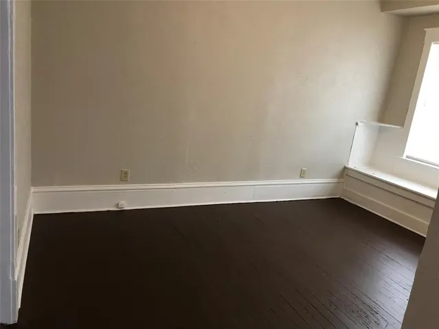 an empty room with wooden floor and window