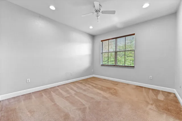 an empty room with a window and a ceiling fan