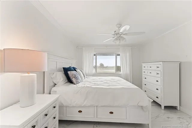 a bedroom with a large bed and a chandelier fan