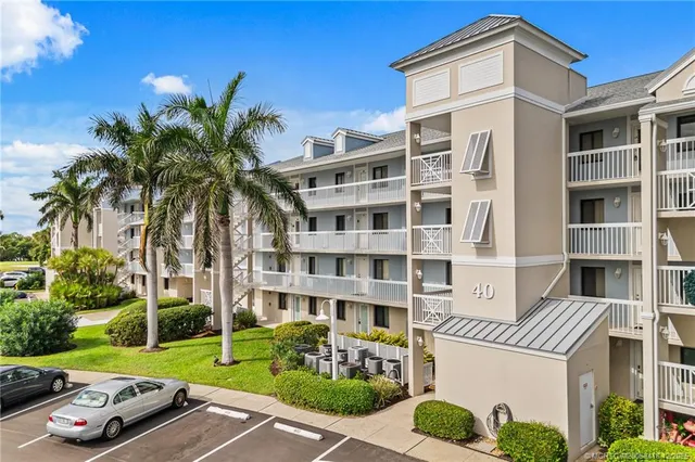 a front view of a residential apartment building with a yard and potted plants