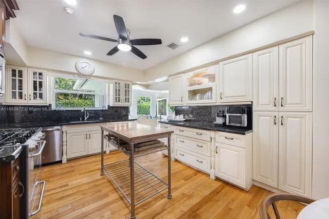 a kitchen with stainless steel appliances granite countertop a stove a sink dishwasher and a refrigerator with wooden floor