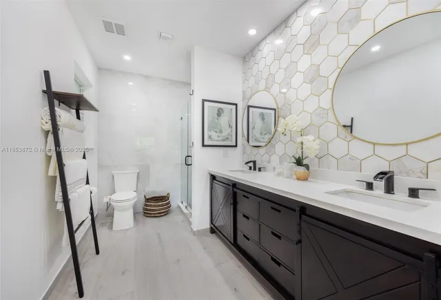 a spacious bathroom with a double vanity sink toilet and mirror