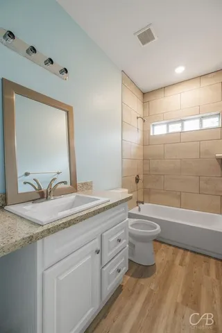 a bathroom with a granite countertop sink toilet a large mirror a bathtub and window