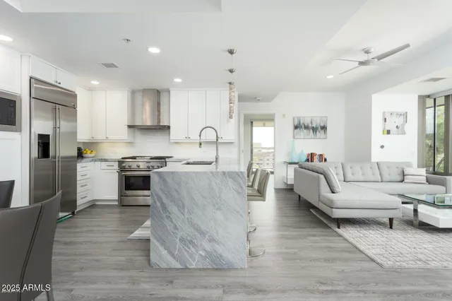 a living room with stainless steel appliances kitchen island granite countertop a stove a sink a refrigerator and cabinets