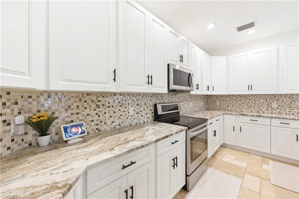 415 Crossfield Circle, Unit 81 Naples, FL 34104 - Photo 13 of 33 a kitchen with granite countertop white cabinets and white appliances