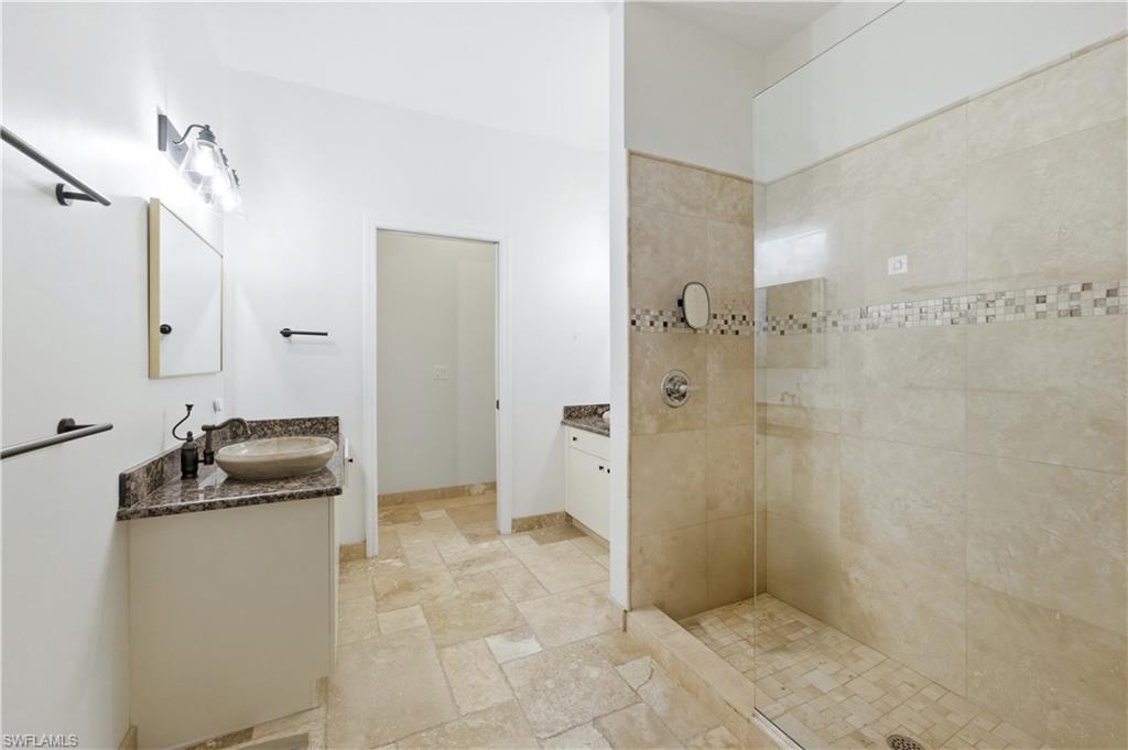 415 Crossfield Circle, Unit 81 Naples, FL 34104 - Photo 9 of 33 a bathroom with a granite countertop sink a mirror and a shower