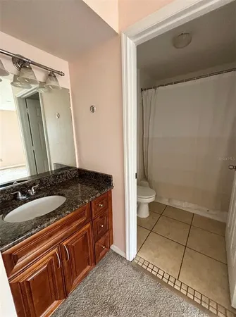a bathroom with a granite countertop sink a toilet a mirror and vanity