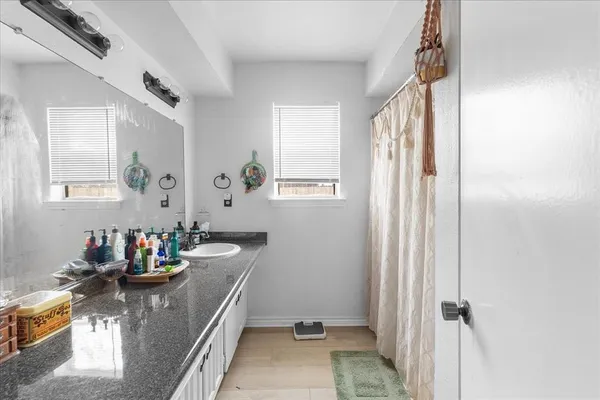 a bathroom with a granite countertop sink a mirror and shower