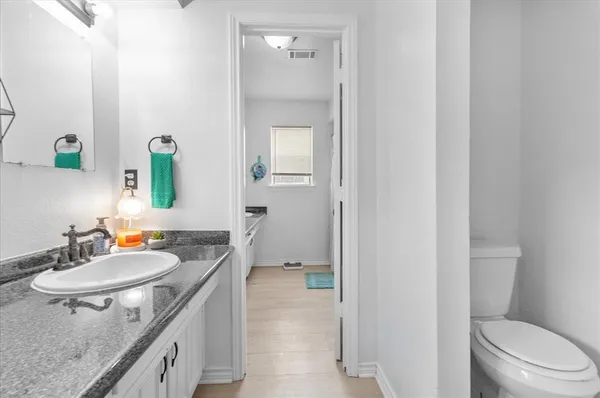 a bathroom with a granite countertop sink a mirror and a toilet