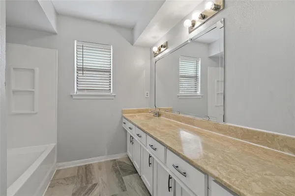 a bathroom with a granite countertop sink and a bathtub