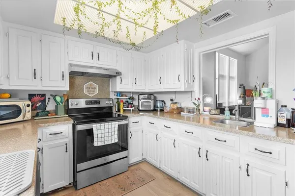 a kitchen with stainless steel appliances granite countertop a stove and white cabinets