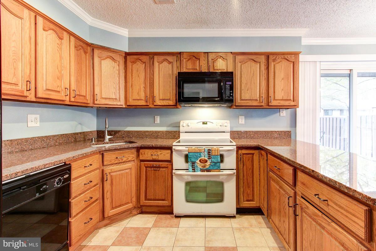 2299 White Cornus Lane Reston, VA 20191 - Photo 14 of 24 a kitchen with stainless steel appliances granite countertop a stove top oven a sink dishwasher and white cabinets with wooden floor