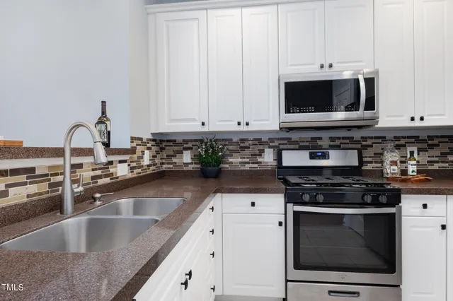 a kitchen with granite countertop white cabinets and stainless steel appliances