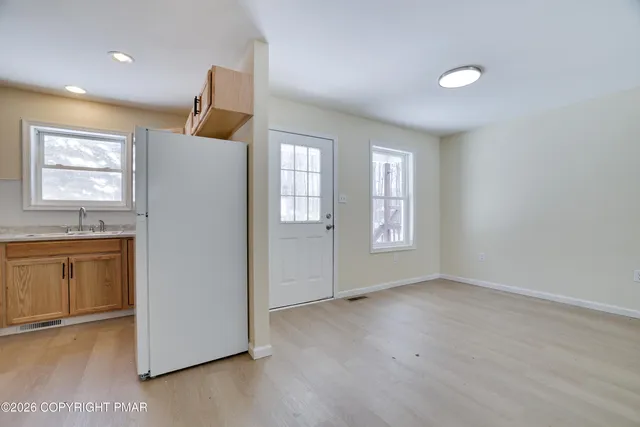 a view of an empty room with window and wooden floor