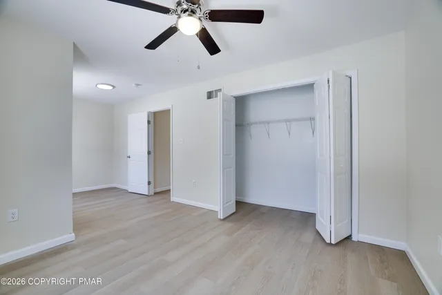 an empty room with wooden floor closet and windows