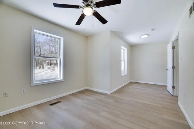 a view of an empty room with window and wooden floor