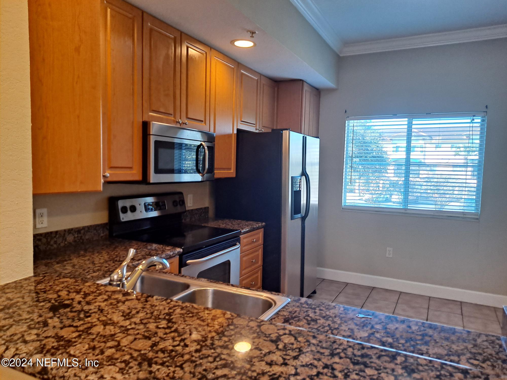 9745 Touchton Road, Unit 927 Jacksonville, FL 32246 - Photo 6 of 22 a kitchen with stainless steel appliances a refrigerator and a stove top oven