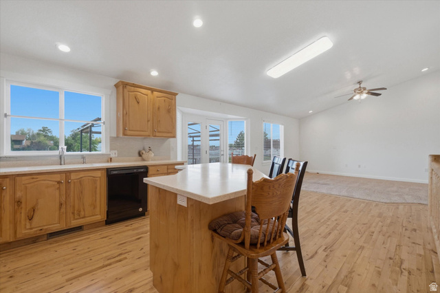 791 East Saddle Road Grantsville, UT 84029 - Photo 5 of 46 Open-concept kitchen featuring light wood cabinetry, a center island with countertop seating, and integrated black appliances