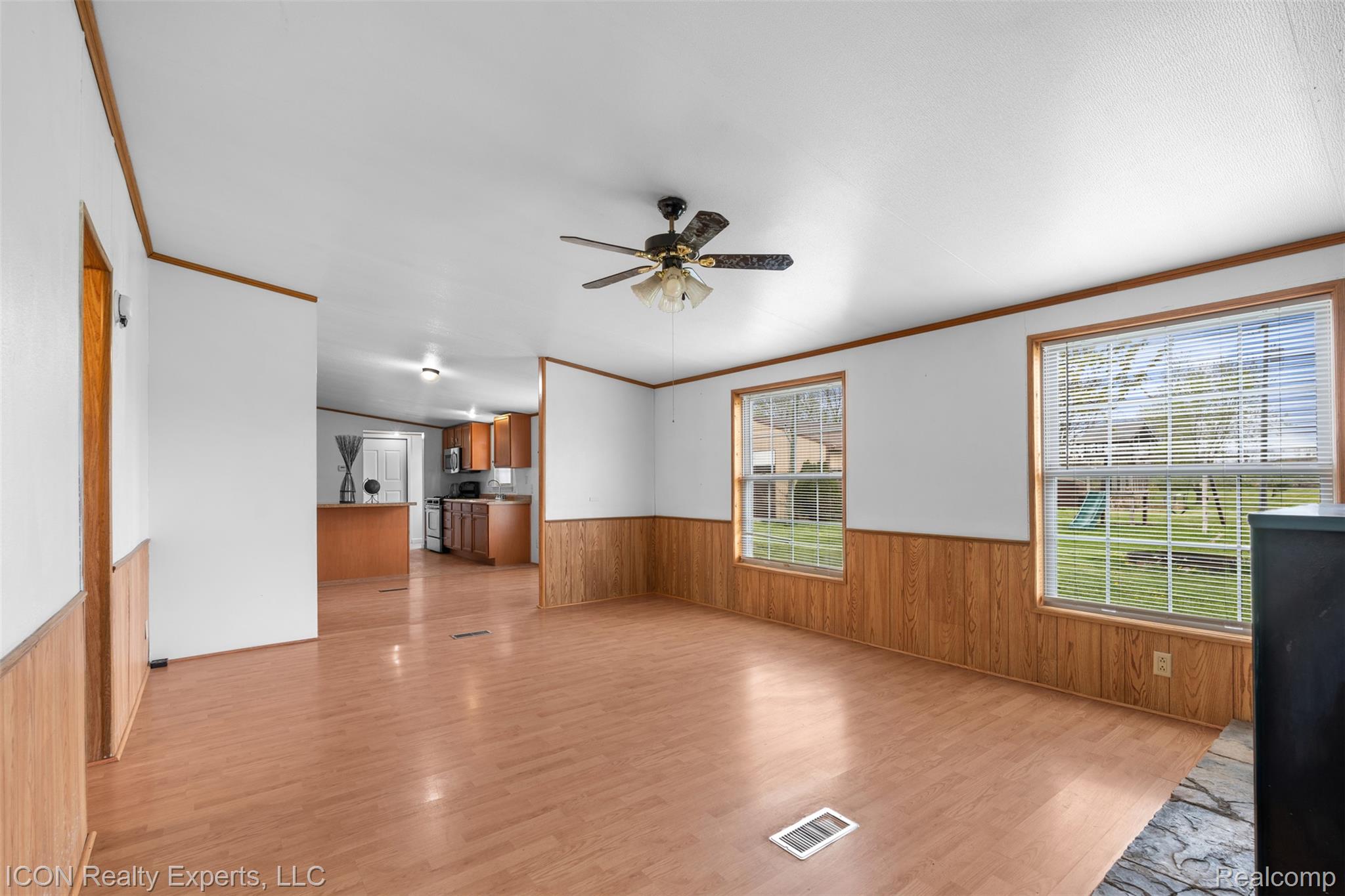 13620 Gilbert Road Allenton, MI 48002 - Photo 13 of 47 Unfurnished living room featuring wood walls, crown molding, wainscoting, light wood-style floors, and a ceiling fan