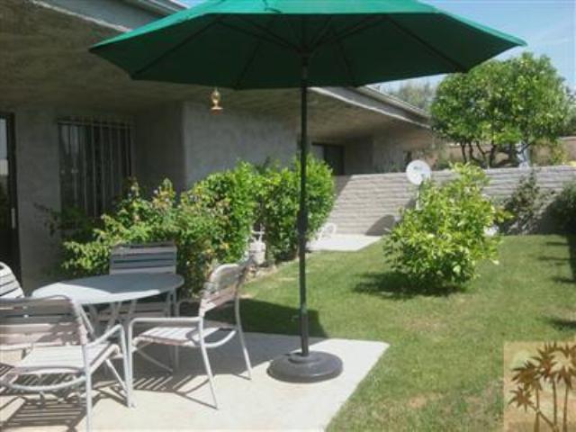 a backyard of a house with table and chairs under an umbrella