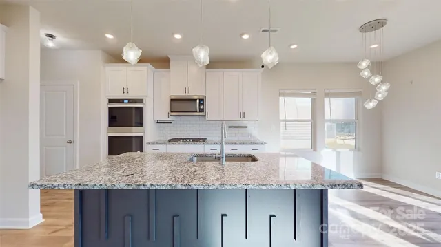 a kitchen with kitchen island granite countertop a sink and stainless steel appliances