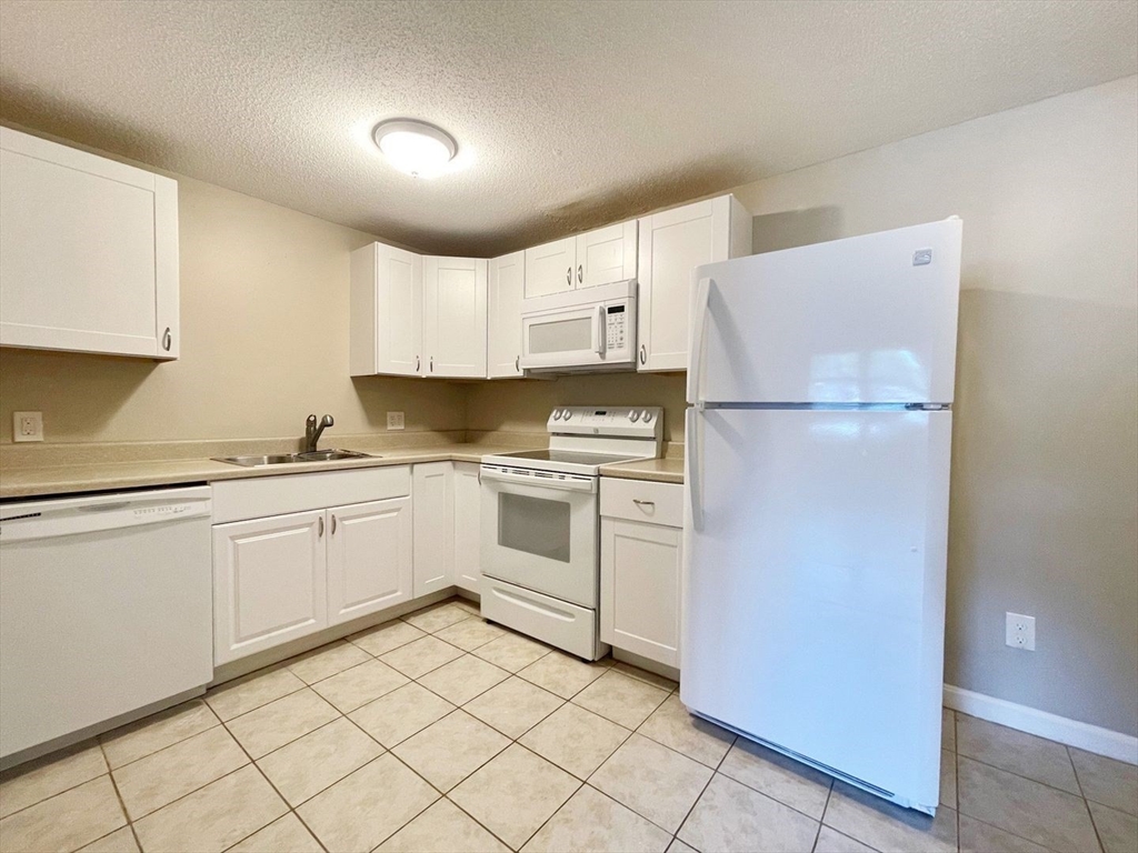 1617 Braley Road, Unit 82 New Bedford, MA 02745 - Photo 7 of 12 a kitchen with white cabinets and white appliances