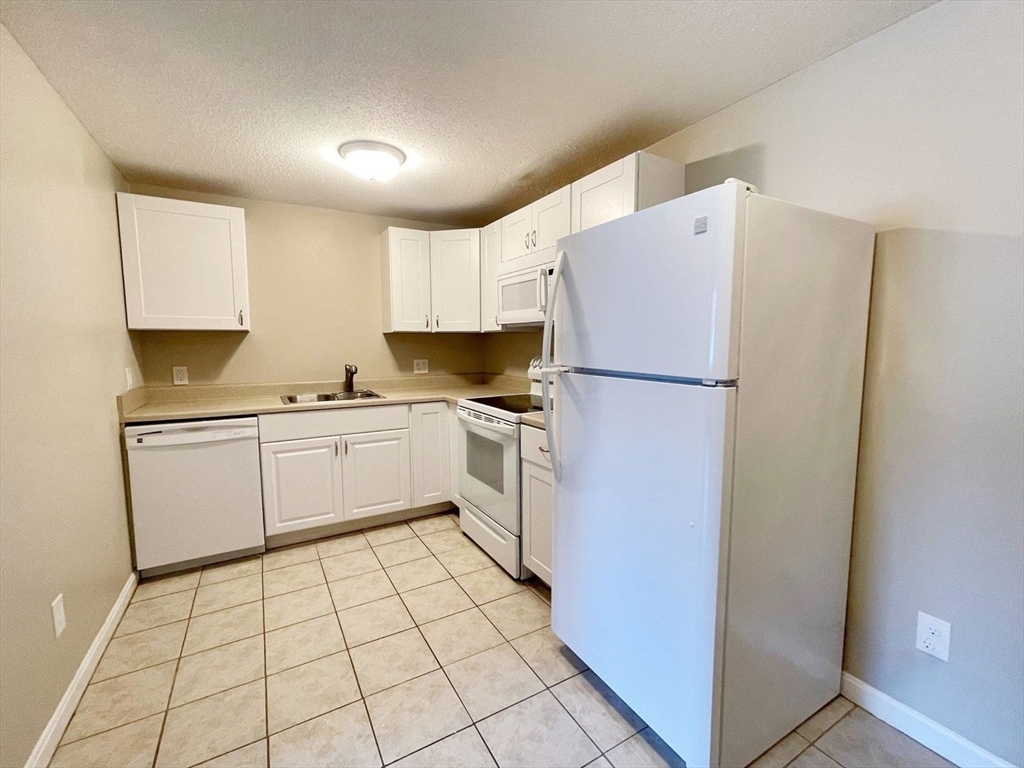 1617 Braley Road, Unit 82 New Bedford, MA 02745 - Photo 8 of 12 a kitchen with white cabinets and white appliances