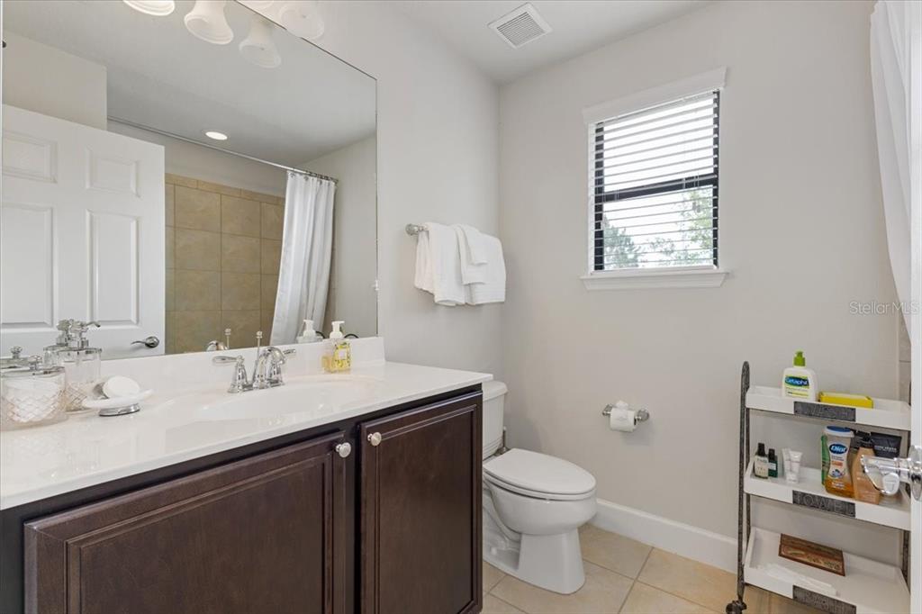 7180 Beek Street Windermere, FL 34786 - Photo 18 of 33 a bathroom with a granite countertop sink a large mirror a toilet and a window