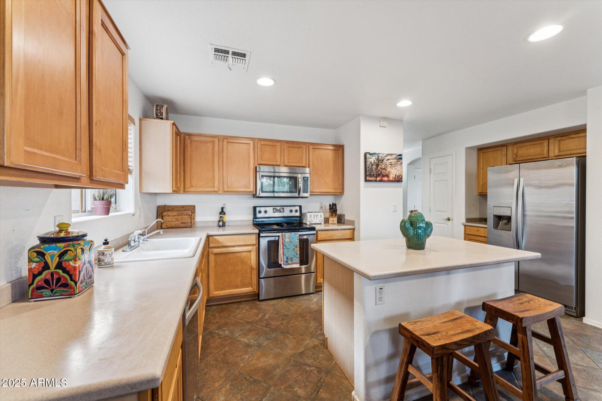 5128 East Via Dona Road Cave Creek, AZ 85331 - Photo 9 of 38 a kitchen with a refrigerator a stove a sink a dining table and chairs with wooden floor