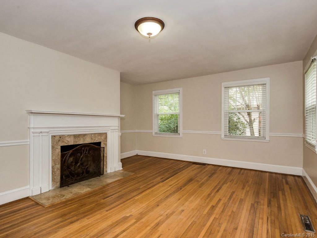 907 Sedgefield Road Charlotte, NC 28209 - Photo 4 of 21 an empty room with wooden floor fireplace and windows