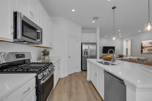 a kitchen with stainless steel appliances granite countertop a sink a stove top oven and refrigerator