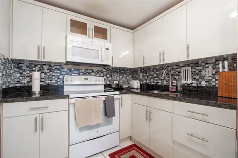 a kitchen with granite countertop white cabinets and white appliances