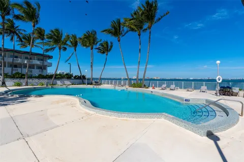a view of a swimming pool with a lawn chairs under an umbrella