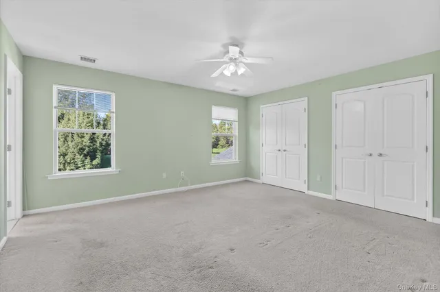 an empty room with chandelier fan and windows