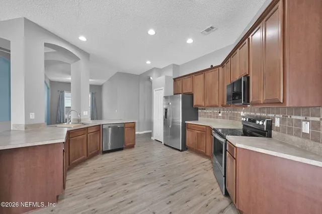 a kitchen with stainless steel appliances granite countertop wooden cabinets a stove top oven a sink and dishwasher