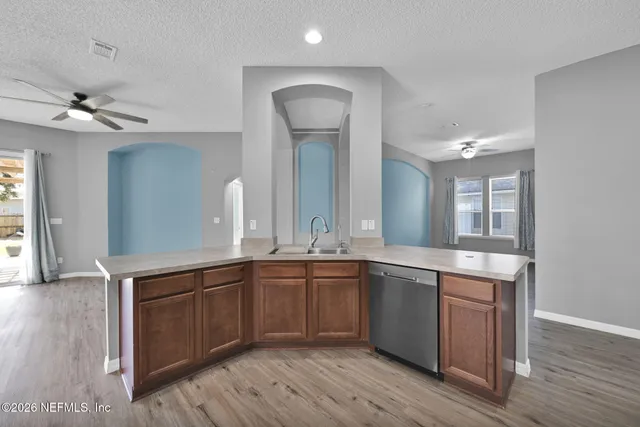 a large kitchen with a sink and dishwasher with wooden floor