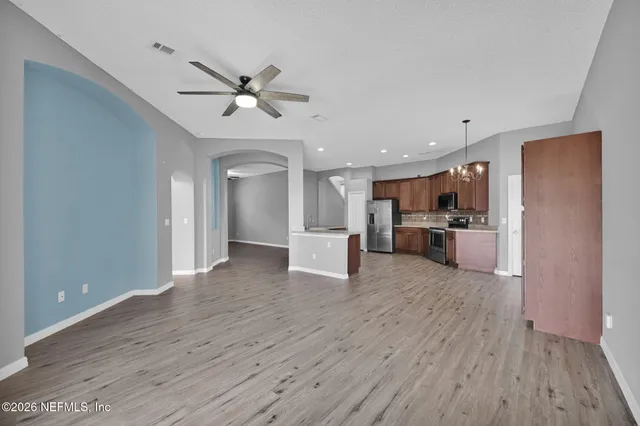 a view of an empty room with kitchen appliances and a ceiling fan