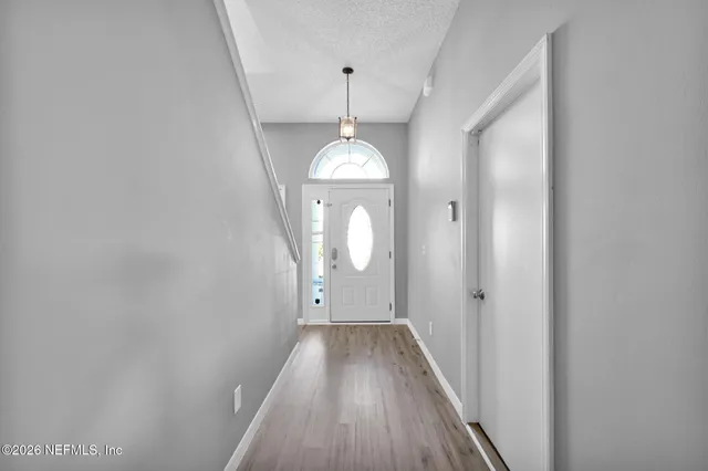 a view of a hallway with wooden floor and chandelier