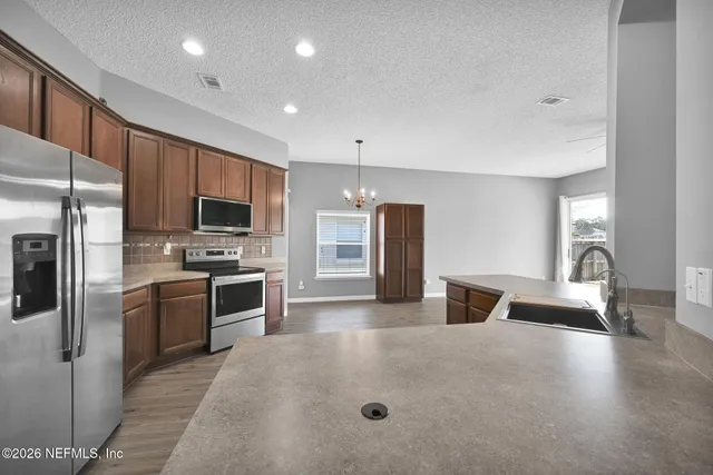 a kitchen with refrigerator a microwave and furniture