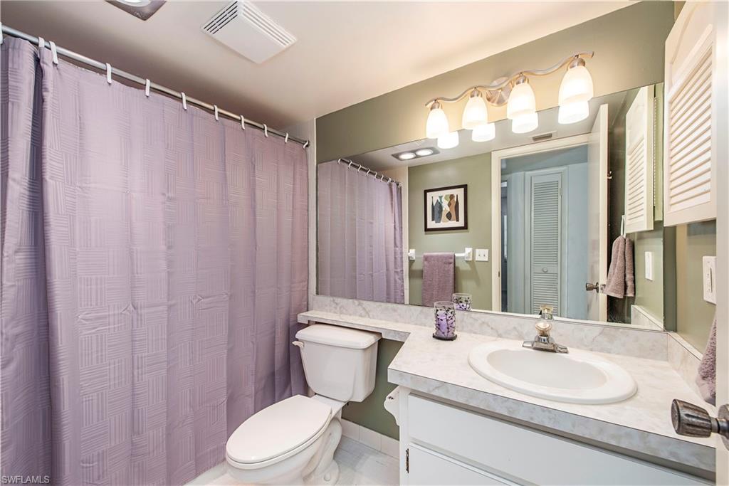 214 Bobolink Way, Unit 214B Naples, FL 34105 - Photo 11 of 12 a bathroom with a toilet a sink and a mirror