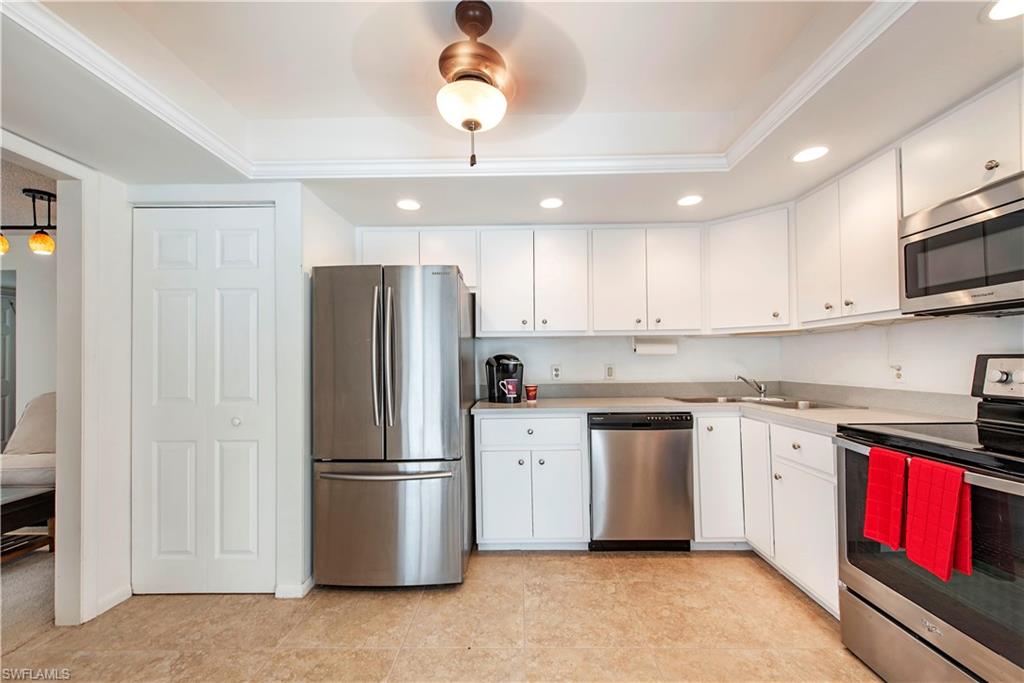 214 Bobolink Way, Unit 214B Naples, FL 34105 - Photo 7 of 12 a kitchen with stainless steel appliances granite countertop a refrigerator stove a sink and dishwasher