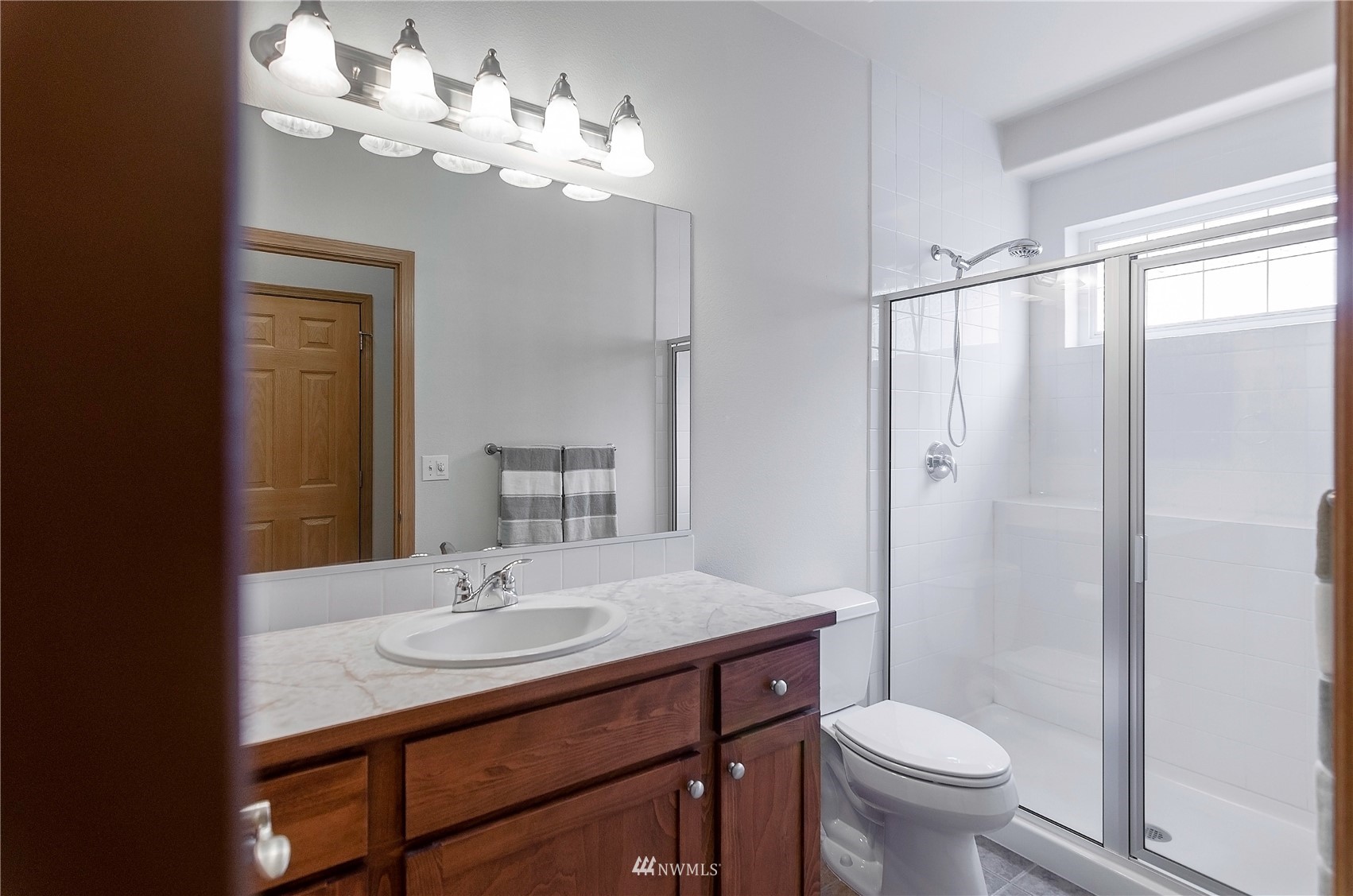 8228 Bainbridge Loop Northeast Lacey, WA 98516 - Photo 17 of 32 a bathroom with a sink a toilet a mirror and shower