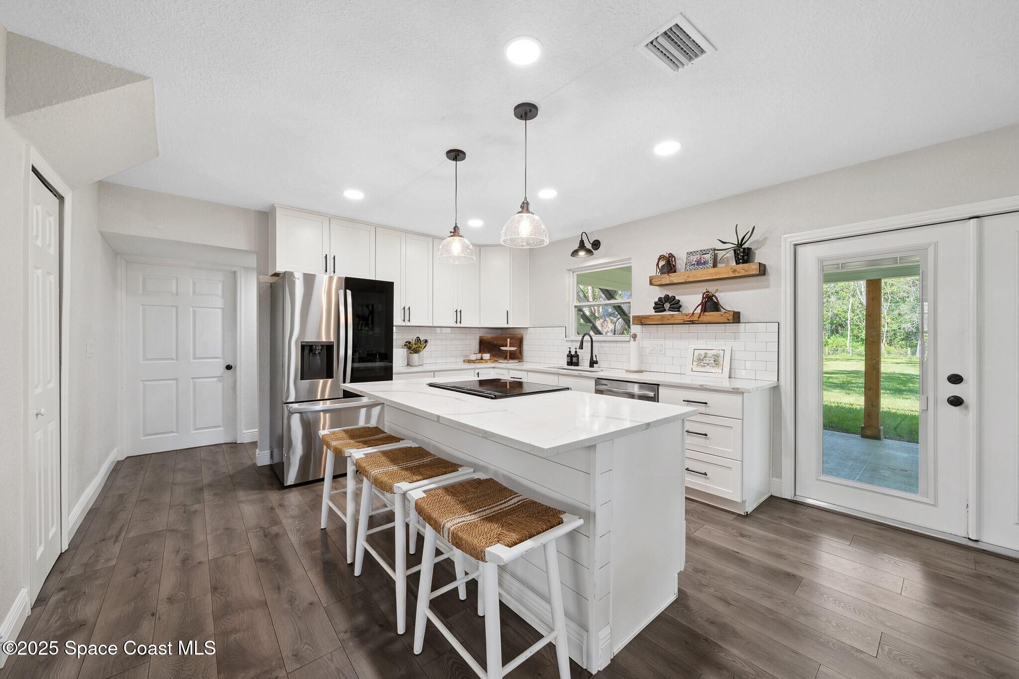 1325 Friday Road Cocoa, FL 32926 - Photo 12 of 59 a kitchen with kitchen island a stove a refrigerator a sink dishwasher with a dining table and chairs