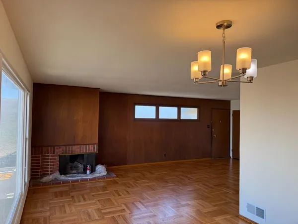 a view of an empty room with a fireplace and chandelier fan