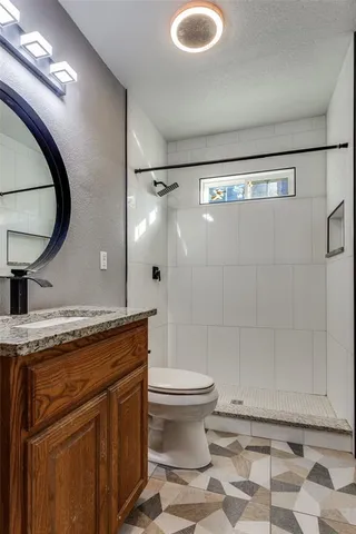 a bathroom with a granite countertop sink mirror vanity and toilet