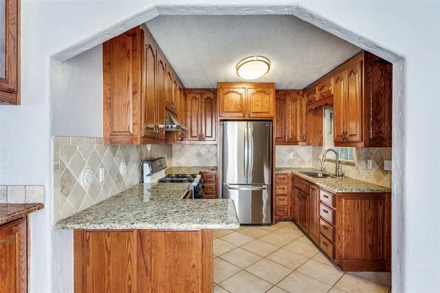 a kitchen with stainless steel appliances granite countertop a refrigerator a stove and a sink