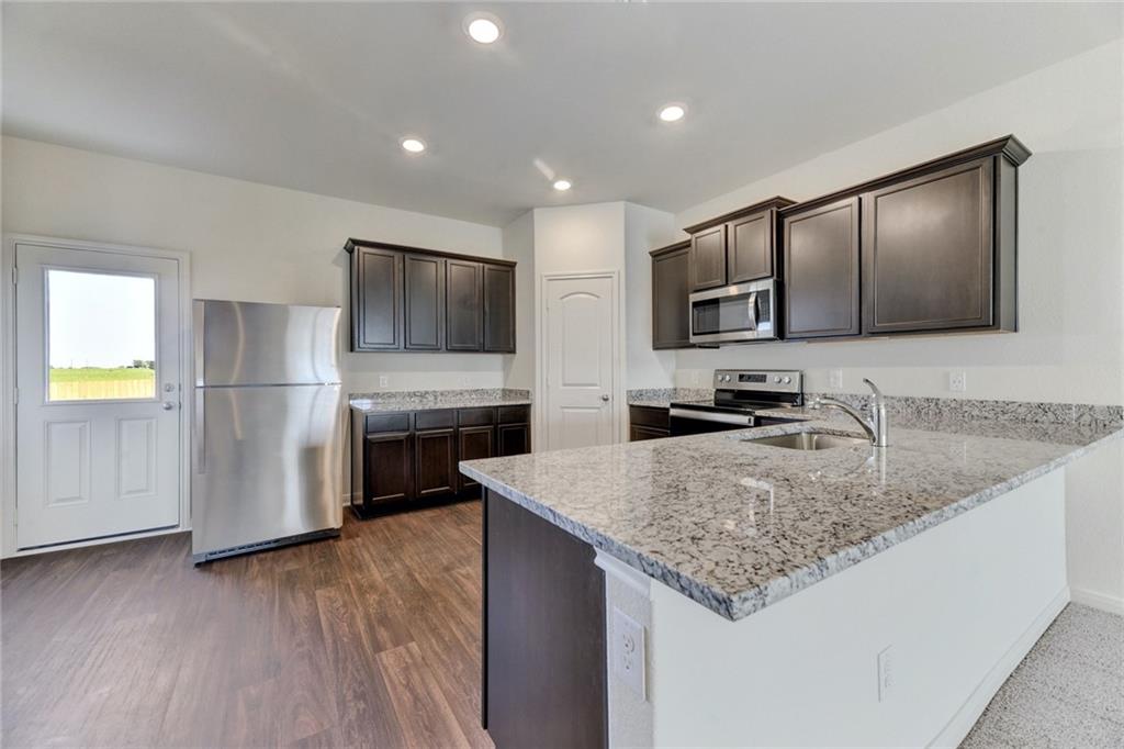 105 Brunswick Lane Jarrell, TX 76537 - Photo 6 of 18 a kitchen with stainless steel appliances granite countertop a sink refrigerator and microwave