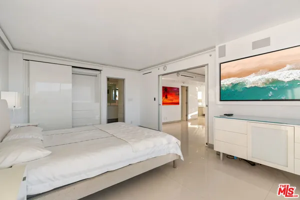 a bedroom with a large bed and a flat tv screen on dresser
