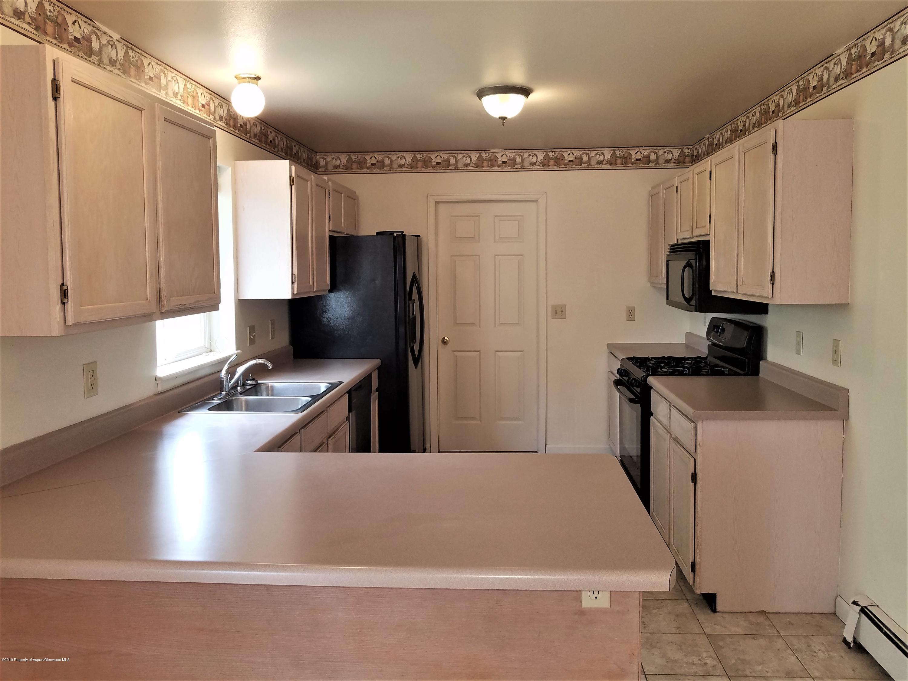 1526 Arabian Avenue Rifle, CO 81650 - Photo 8 of 20 a kitchen with stainless steel appliances a refrigerator a sink a stove and white cabinets