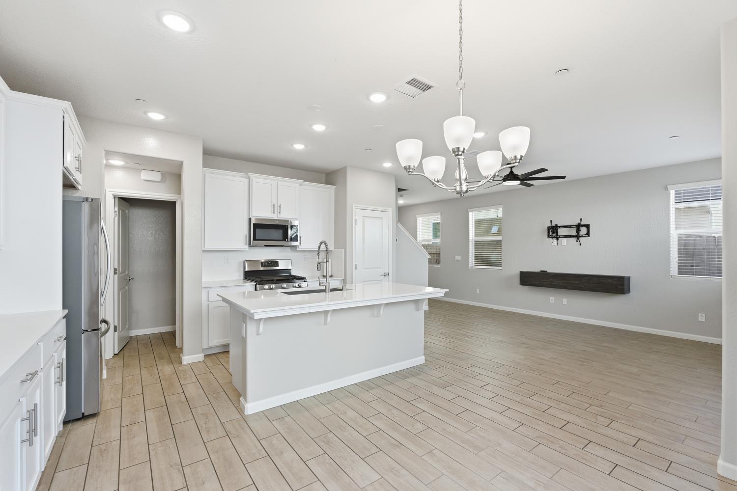 1107 Significant Way West Madera, CA 93636 - Photo 15 of 42 a large kitchen with granite countertop a stove a sink dishwasher a refrigerator and a fireplace with wooden floor